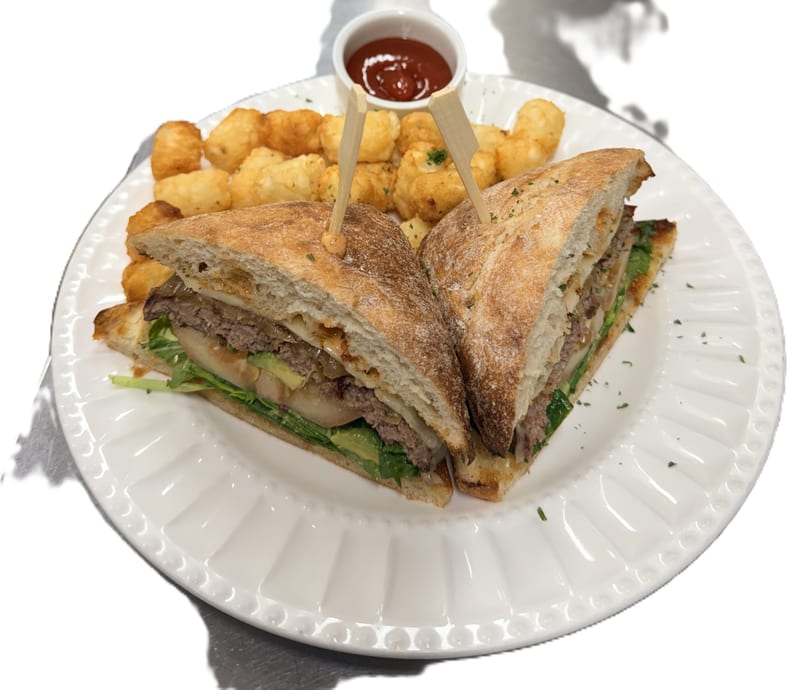 A steak sandwich with avocado, lettuce, and cheese, served with tater tots and ketchup.