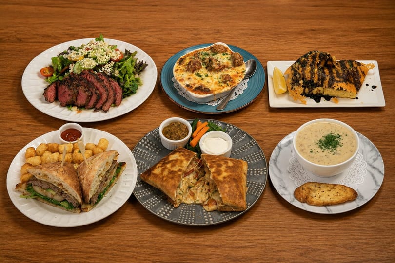 Six diverse dishes, including steak salad, baked meatballs, grilled polenta, sandwich, quesadilla, and soup.